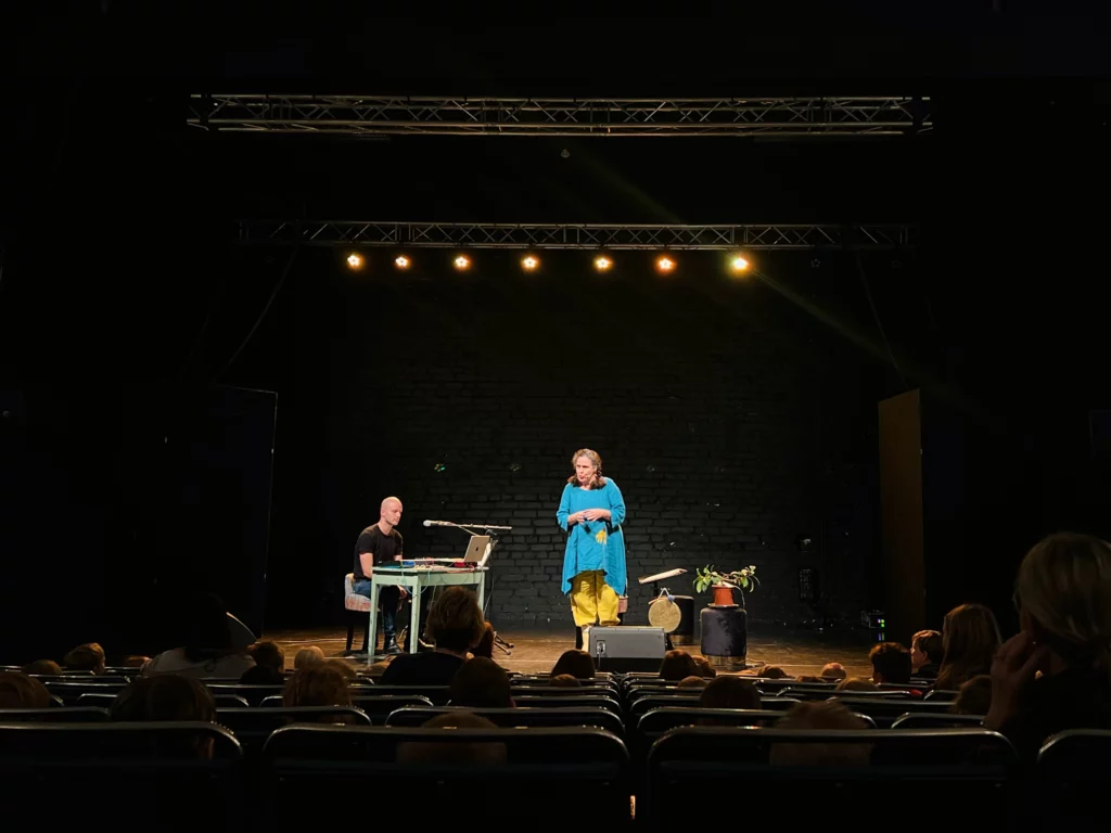 Två konstnärer står på Karelias scen framför en barnpublik.Kaksi taiteilijaa seisoo Karelian näyttämöllä lapsiyleisön edessä.